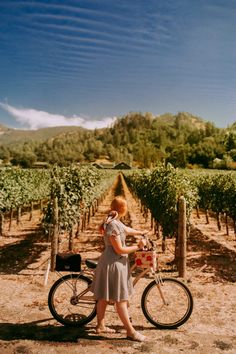 a woman standing next to a bike in a vineyard