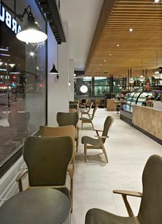 the inside of a restaurant with chairs and tables in front of glass windows that have lights on them