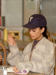 a woman sitting at a table in front of a book with her hands clasped together