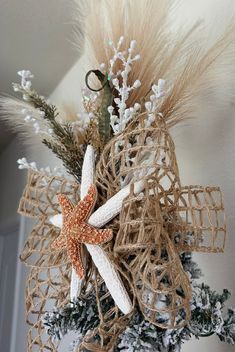 a starfish decoration hanging from the side of a christmas tree with white and brown decorations