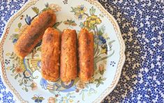 three sausages are on a plate with blue and white floral designs around the edges