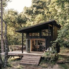 a small cabin in the woods with stairs leading up to it