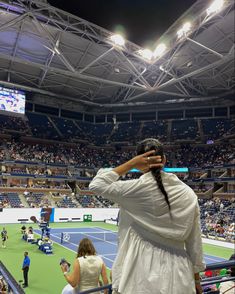 a woman in white dress standing on top of a tennis court