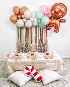 a table topped with balloons and candy canes next to a gingerbread man balloon