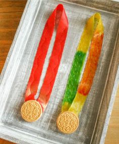 two gold medals are sitting on a tray with red, yellow and green ribbons around them