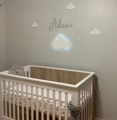 a baby's room with a crib and clouds on the wall