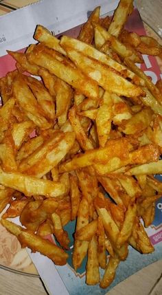 french fries are piled on top of each other in front of a paper wrapper