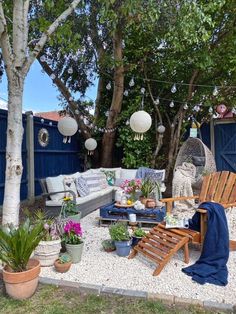 an outdoor living area with chairs, couches and potted plants in the foreground