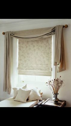 a window with roman shades and pillows in front of the window is decorated with flowers