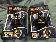 two lego batman keychains sitting on top of a bed