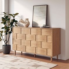 a wooden dresser sitting next to a potted plant on top of a hard wood floor