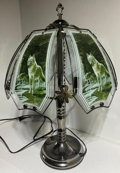 a silver lamp with two mirrors on it's sides and an image of three wolfs in the background