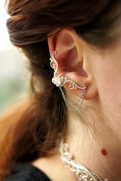 a close up of a person wearing some kind of ear cuff with pearls on it