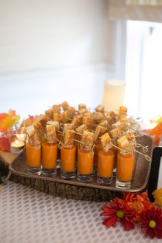 there are many small cups with food in them on a tray next to flowers and candles