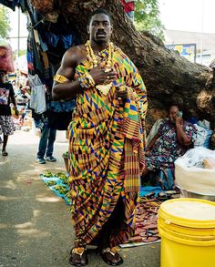 a man dressed in african clothing standing next to a tree