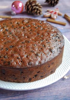 a cake sitting on top of a white plate next to pine cones and cinnamon sticks