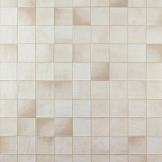 a white tiled wall with different shades of beige