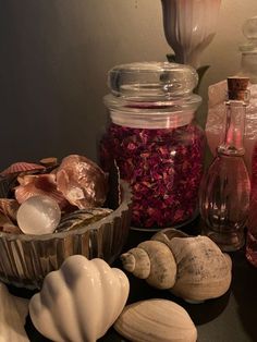 sea shells and other seashells sit on a table in front of a glass jar