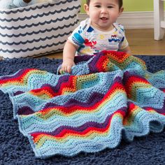 a baby is sitting on the floor with a crocheted blanket in front of him