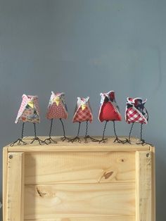 five little birds are sitting on top of a wooden box and one is wearing an apron