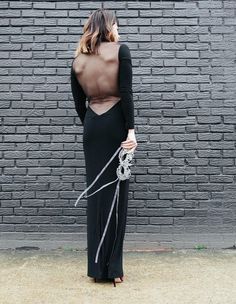 a woman standing in front of a brick wall with her back turned to the camera