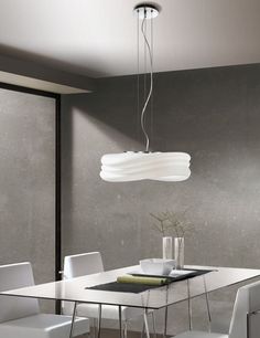 a dining room table with white chairs and a light fixture hanging from it's ceiling