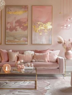 a living room with pink couches and paintings on the wall above them, in front of a coffee table