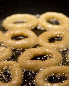 some donuts are cooking in a frying pan with oil on them and sprinkled