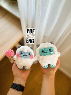 someone holding up two small crocheted sheeps