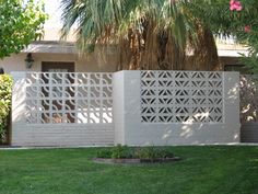 an image of a white fence in front of a house with palm trees on the other side