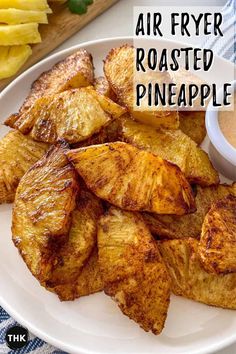 air fryer roasted pineapples on a white plate with a bowl of dipping sauce