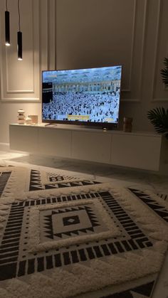 a flat screen tv sitting on top of a white shelf in a living room next to a potted plant