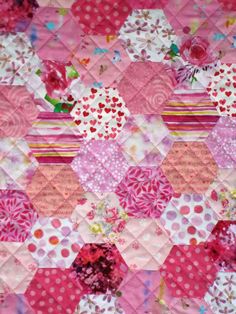 a pink and red patchwork quilt with flowers on it