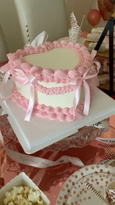 a pink and white cake sitting on top of a table next to other desserts