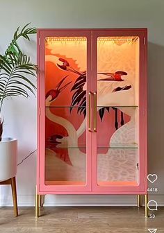 a pink cabinet with flamingos painted on the glass doors and gold trimmings