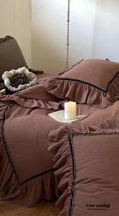 a bed that has some pillows on it and a candle in front of the pillow