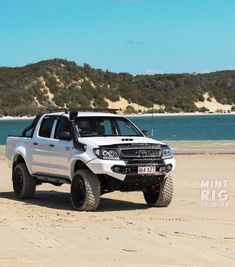 a white truck parked on top of a sandy beach