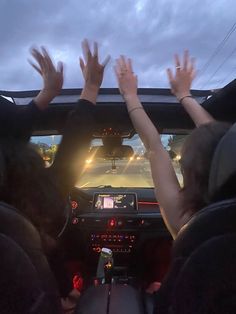 two people sitting in the back seat of a car with their hands up