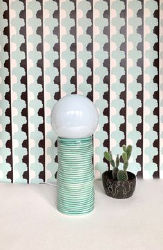 a white vase sitting on top of a table next to a cactus