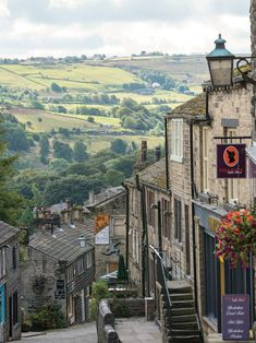 an alley way with stone buildings and green hills in the background