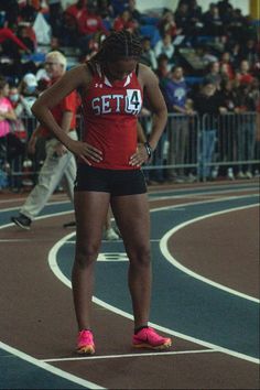 a woman standing on top of a track next to a crowd