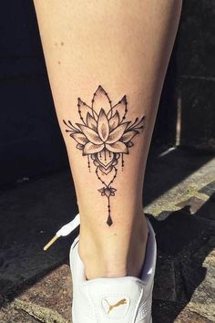 a woman's foot with a flower tattoo on the side of her leg and an arrow