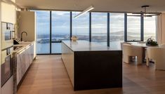 an open kitchen and dining area with large windows overlooking the cityscape in this modern home