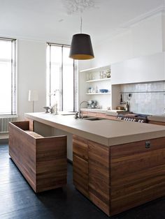 an island in the middle of a kitchen with lots of counter space and lighting above it