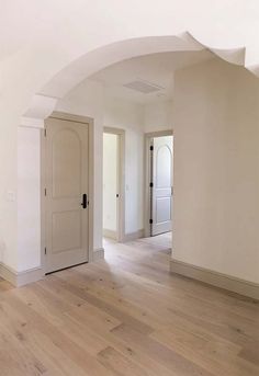 an empty living room with white walls and wood floors is pictured in this image from the doorway