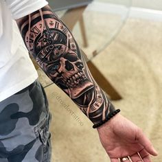 a man with a clock and skull tattoo on his arm is holding the hand of another person