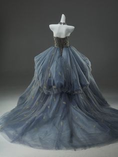 a blue dress with gold stars on the bustle and skirt is displayed in front of a white mannequin