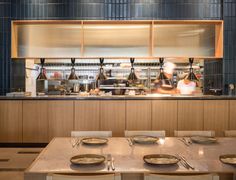 a restaurant kitchen with two chefs preparing food behind the counter and plates on the table