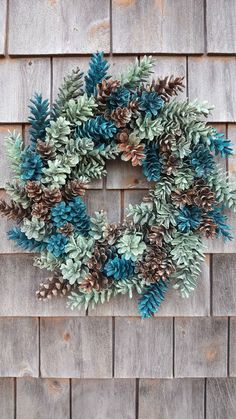 a wreath made out of pine cones and evergreen leaves on a wooden wall with the words,