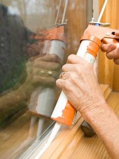 a man is painting a window with an orange sprayer